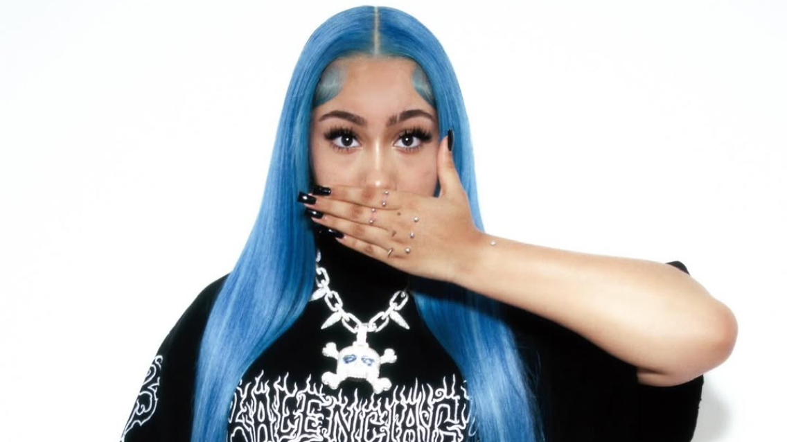 North West showing blue hair and decorative hand jewelry in a portrait